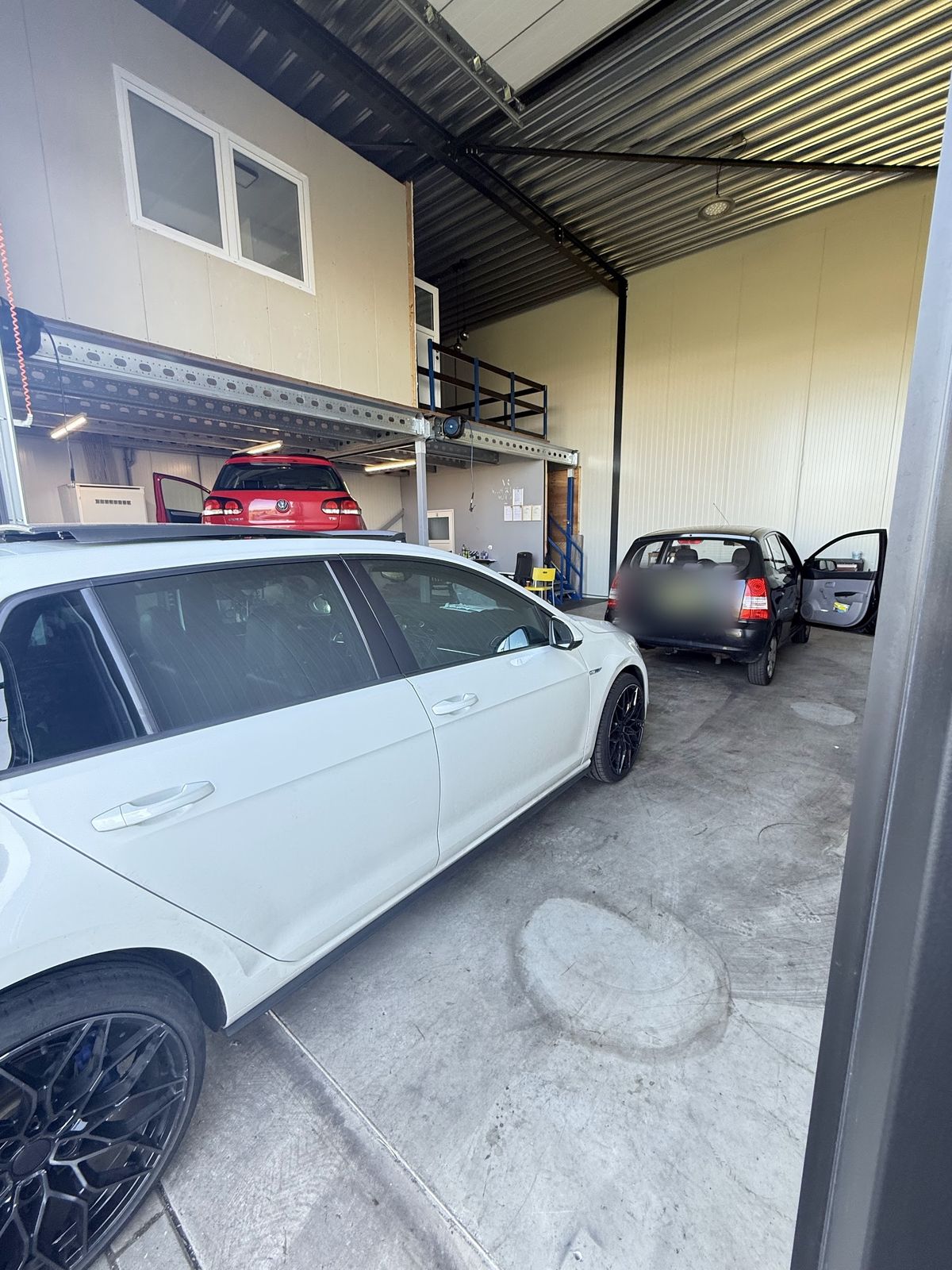 Binnen in de werkplaats: twee auto's onder de entresol