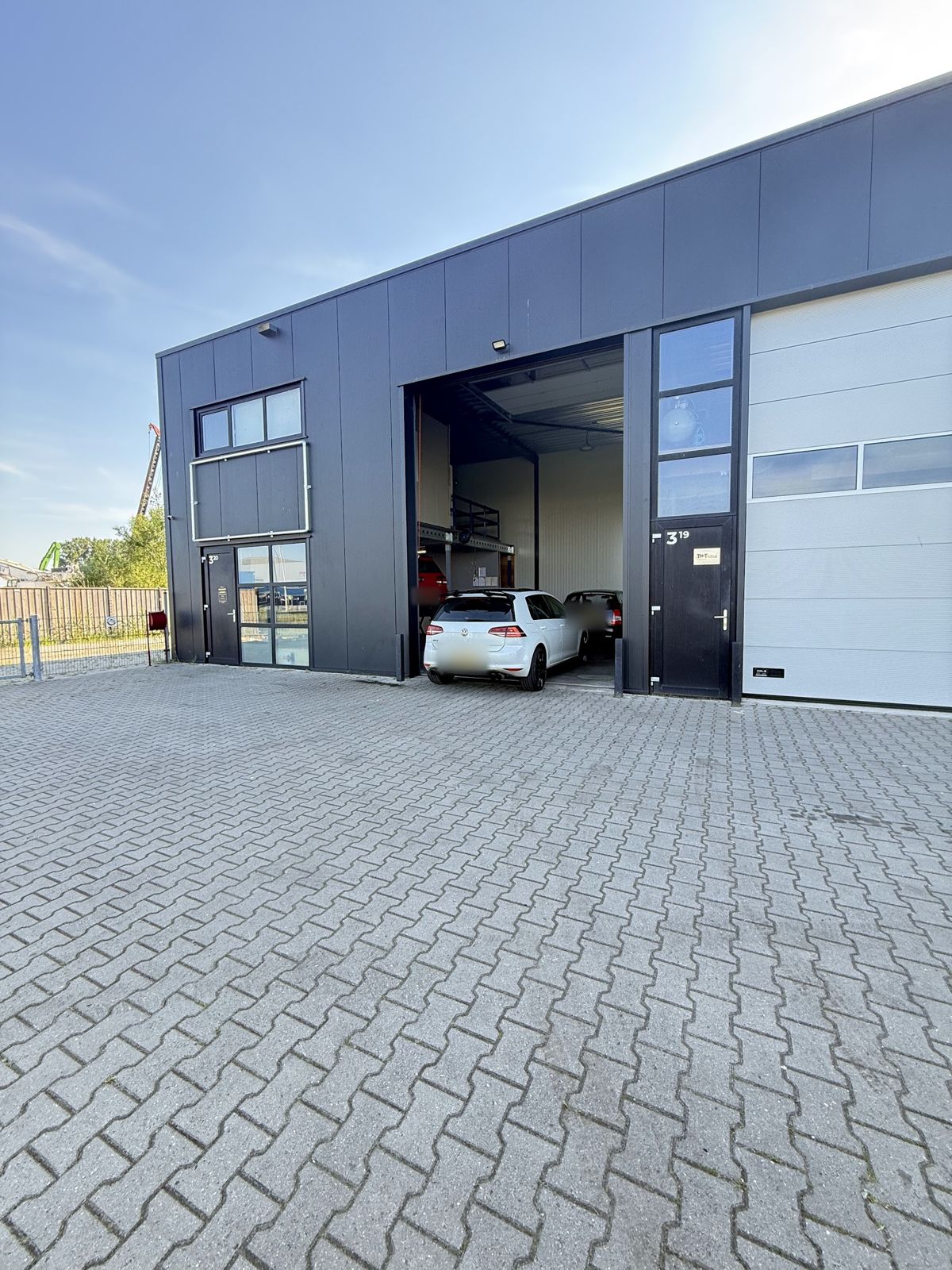 Het bedrijfspand van Autoservice CS4 met de roldeur open en een auto in de werkplaats