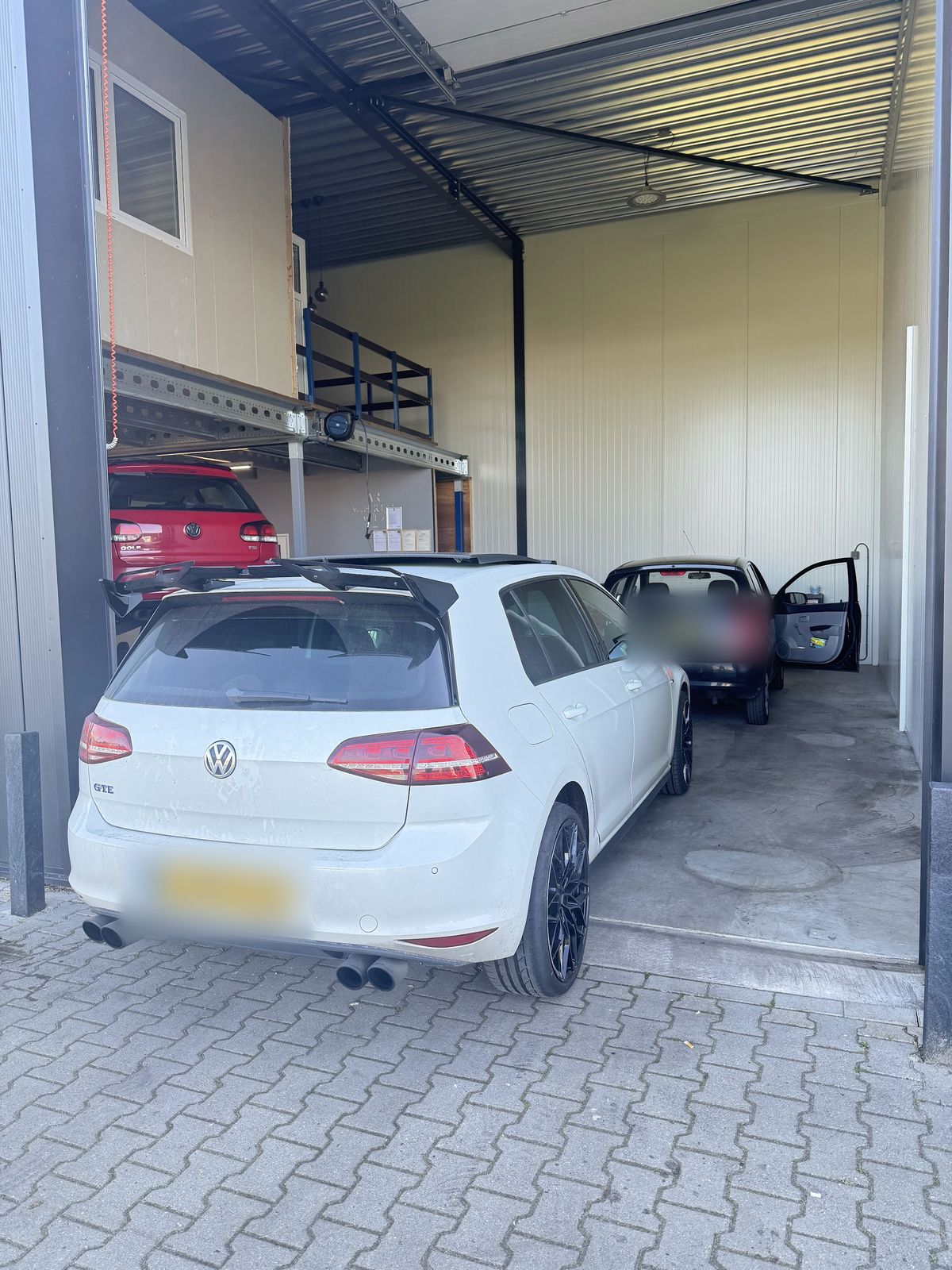 Witte Volkswagen Golf in de open roldeur van de werkplaats
