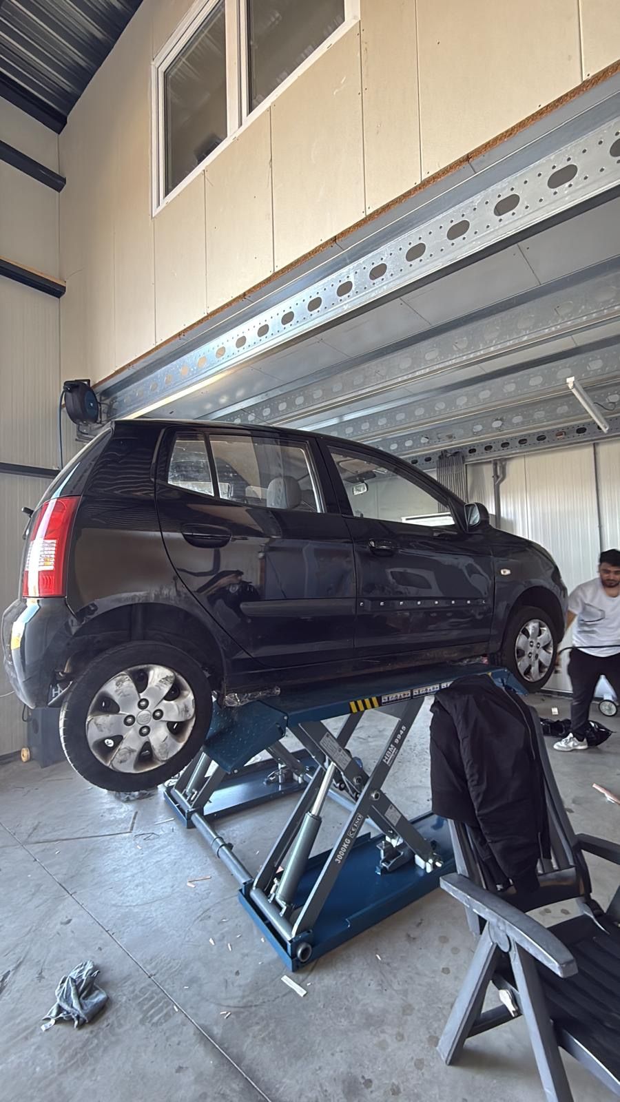 Een auto op de schaarbrug in de werkplaats